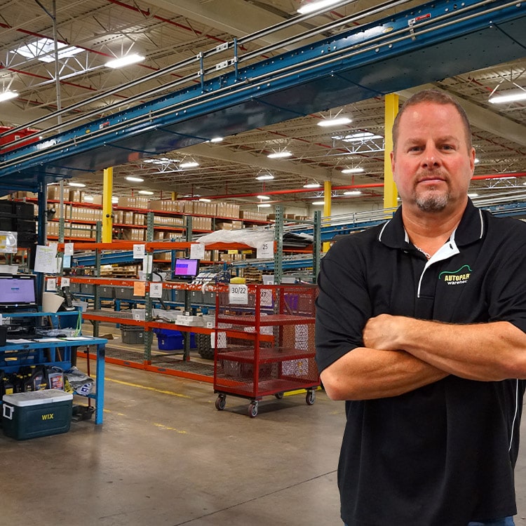 A man standing with his arms crossed in a warehouse.